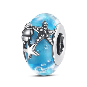 Vista macro de una cuenta de vidrio de Murano azul cielo con dijes de concha y estrella
