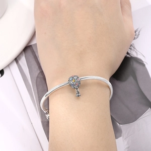 Detalle de pulsera de cadena de plata con dije de globo de mariposa en esmalte colorido
