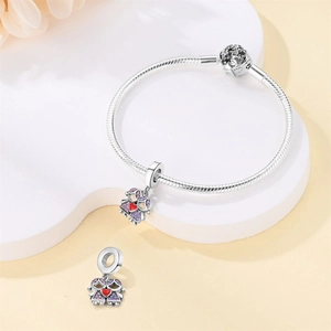 Detalle de pulsera de serpiente plateada con colgantes de niñas y piedras de circonio