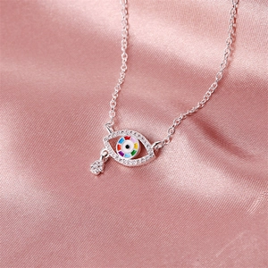 Evil eye pendant necklace with Hamsa hand charm and crystals on pink satin backdrop