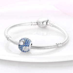 Detalle de pulsera de cadena de serpiente plateada con dijes de concha en circón azul