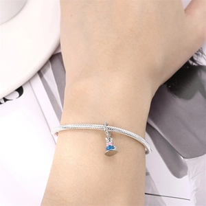 Silver snake chain bracelet with pink and blue cartoon enamel charm worn on hand