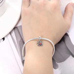 Detalle de una pulsera de cadena de serpiente plateada con colgante de niñas y corazón