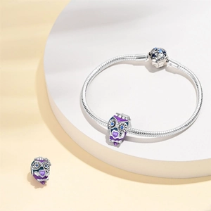 Detailed shot of silver bracelet with purple owl charms and blue heart zirconias