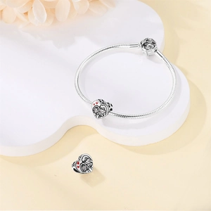 Detalle de pulsera de cadena de serpiente plateada con dijes de corazón y parejas