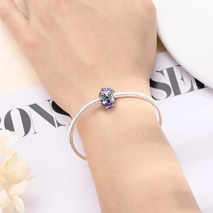 Detailed view of silver snake chain bracelet with purple enamel owl graduation charm