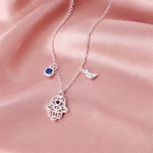 Detail of silver Hamsa Hand necklace with blue gemstone and crescent moon pendant