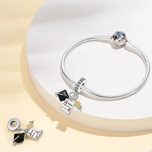 Detail of silver graduation charm bracelet with academic cap and sunflower pendants