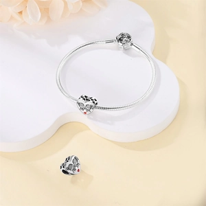 Detalle de los dijes de corazón en una pulsera de cadena de serpiente plateada sobre soporte