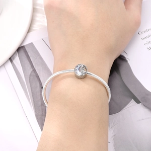 Detailed view of a silver snake chain bracelet with a moon and castle charm featuring zircons