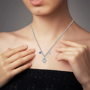 Detail of silver Hamsa hand, crescent moon, and blue gem charms on a delicate chain