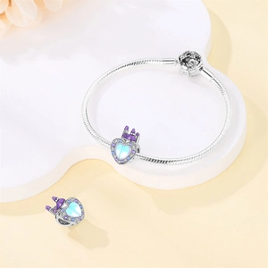 Detailed shot of silver heart charm with purple enamel castle and light blue stone