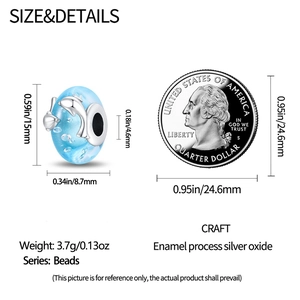 Detalle del dije de delfín en esmalte azul con medidas 15x8,7 mm junto a una moneda de escala