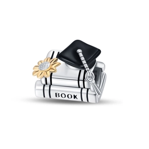 Macro shot of silver graduation charm with books, black academic cap, and golden flower