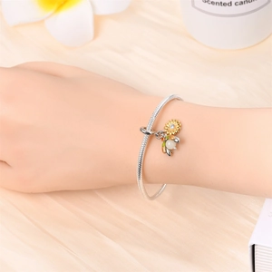 Silver snake chain bracelet with sunflower and honeybee charms on silk background