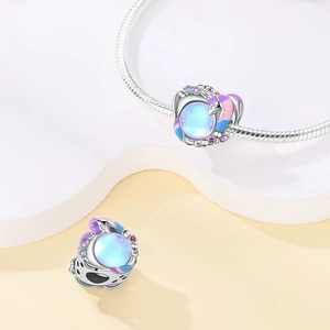 Macro view of silver unicorn charm with blue gemstone and pink enamel wings on a bracelet