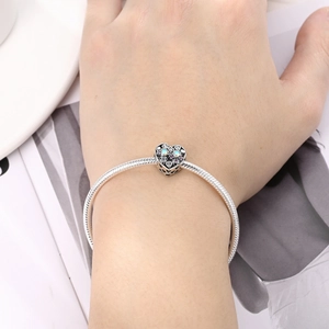 Detalle de una pulsera de plata con colgante de corazón y piedras de colores