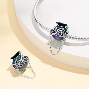 Detail of silver owl charm with graduation cap and colorful glitter on a snake chain