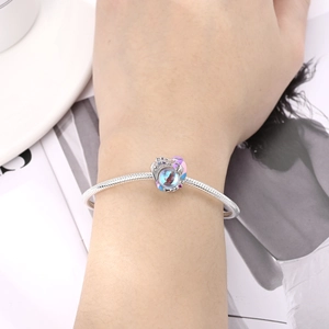 Close-up of heart charm bracelet with colorful enamel and blue stone on a snake chain