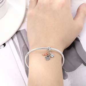 Detalle de pulsera de cadena de serpiente de plata con dijes de corazón y flores