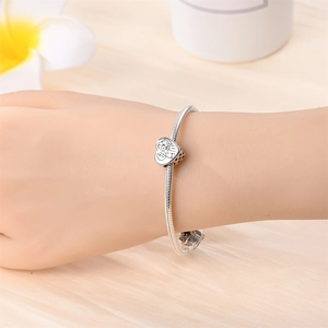 Close-up of a silver snake chain bracelet with a heart-shaped Snoopy cartoon charm