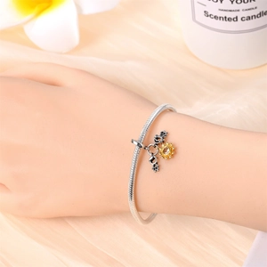 Close-up of a silver sunflower charm bracelet with sparkling zircons on a soft satin background