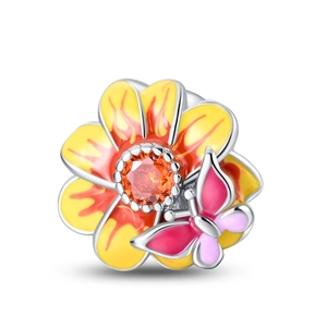 Macro detail of enamel flower charm with butterfly and orange gemstone in silver