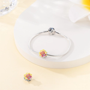 Macro shot of silver snake chain bracelet with floral enamel charms and crystals