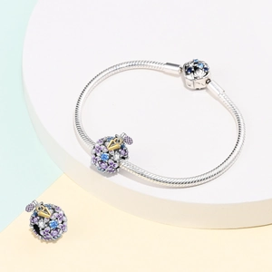 Detail of floral enamel charm on silver snake chain bracelet with sparkling crystals