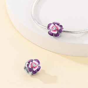 Macro view of silver snake chain bracelet featuring purple and pink enamel flower charms