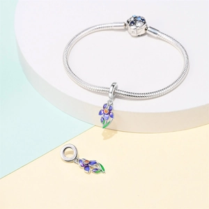 Gros plan d'un bracelet maille serpent avec fleur en émail violet et breloque cristal bleu