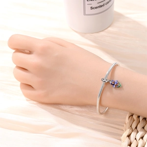 Bracelet chaîne serpent argenté avec pendentif fleur en émail violet et bleu au poignet