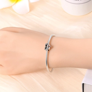 Detailed view of silver snake chain bracelet with heart charms worn on a wrist
