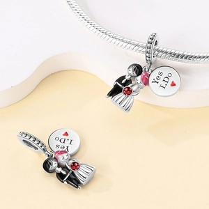 Macro detail of bride and groom charms with Yes I Do engraved silver heart tag