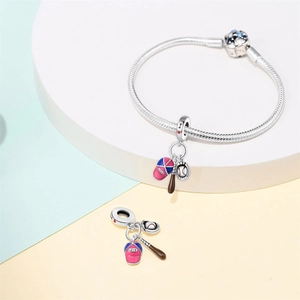 Detail of silver baseball charm bracelet with cap and bat on a minimalist platform