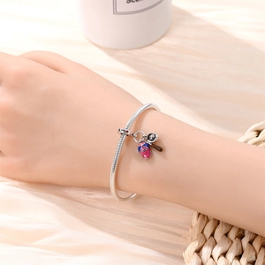 Detail of silver snake chain bracelet with baseball bat and glove charms on wrist