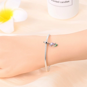 Detailed shot of a silver snake chain bracelet featuring a colorful tulip flower charm