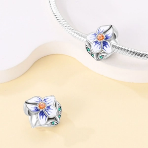 Detailed close-up of blue flower charms with orange center on a silver snake chain