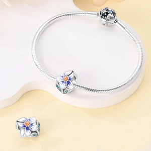 Detail of silver snake chain bracelet with floral enamel charms and orange gemstones