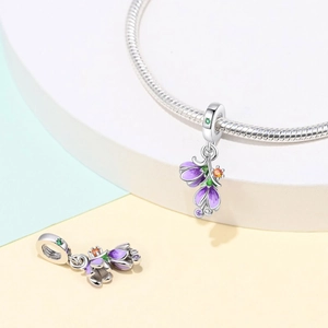 Macro detail of silver floral charm with purple enamel petals and vibrant colorful zircons