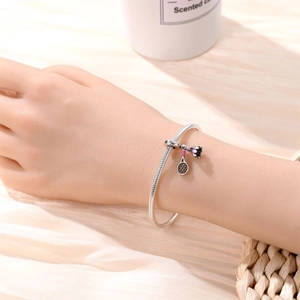 Detail of silver snake chain bracelet featuring tennis racket and badminton charms