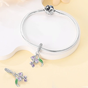 Macro detail of silver charm bracelet with purple floral enamel and zircon clasp inlay