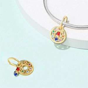 Artistic gold palette charm with colorful gemstones and brush detail on a silver bracelet
