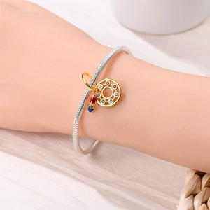 Detail of silver snake chain bracelet with golden palette pendant and colorful gems