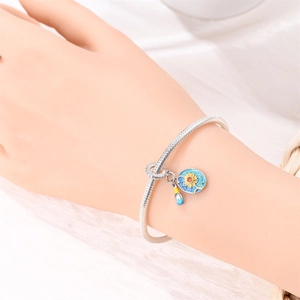Detail of silver snake chain bracelet with sunflower enamel and bottle charms on wrist