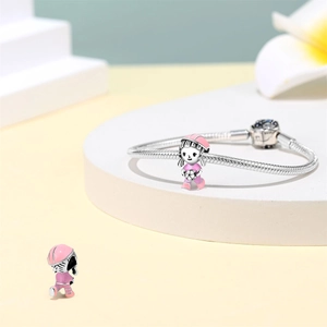 Detail of silver snake chain bracelet with pink enamel soccer girl charm on white platform