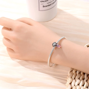 Detail of 925 silver snake chain bracelet with a pink enamel cartoon character charm