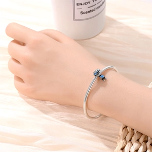 Close-up of a silver-plated snake chain bracelet featuring a blue enamel soccer charm