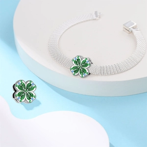 Dettaglio bracciale in maglia d'argento con ciondoli quadrifoglio smaltati e zirconi blu