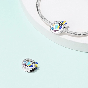 Macro detail of silver painter's palette charm with colorful enamel and ART engraving